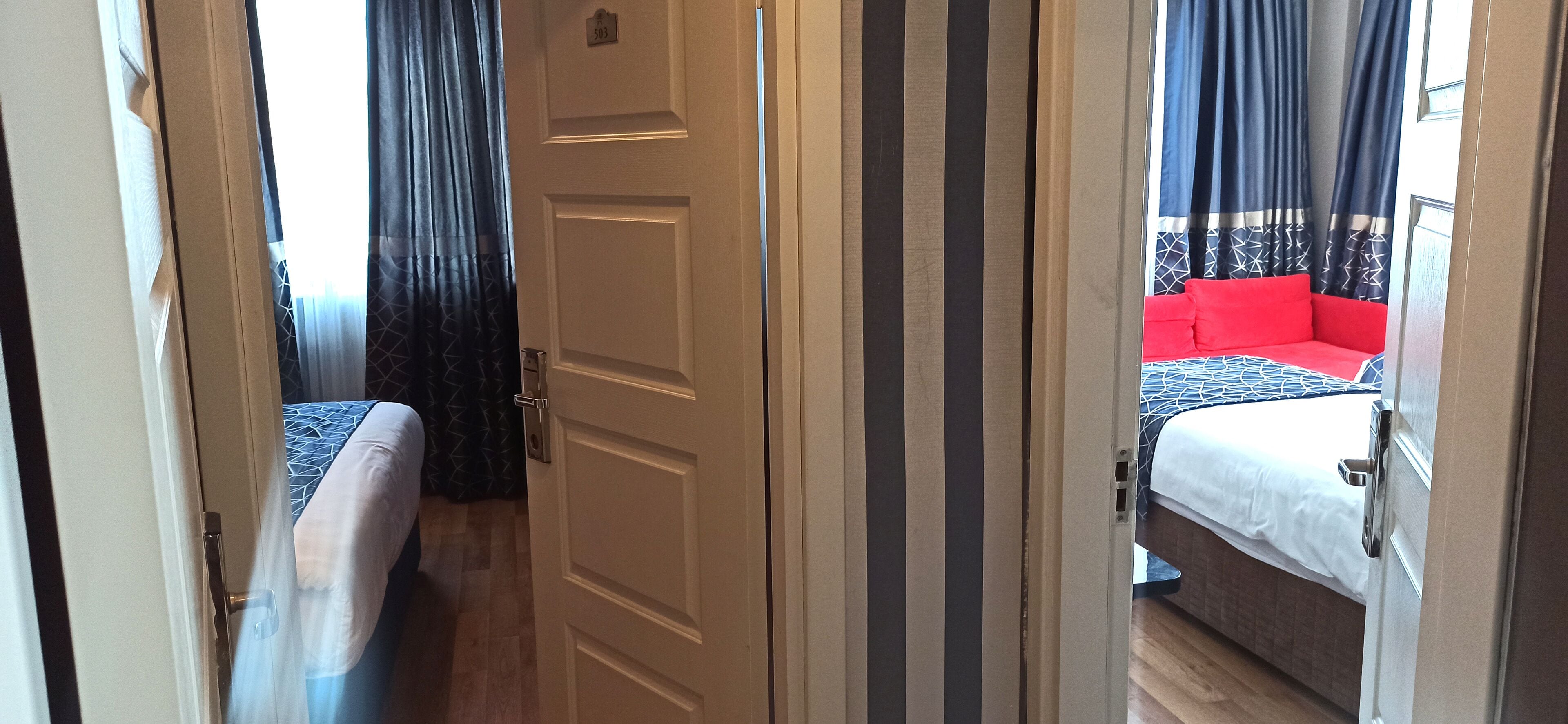 Een hotelkamer met een bed, nachtkastje en een raam met gordijnen.