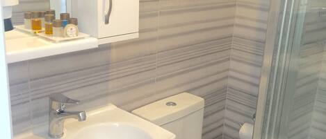 A bathroom with a sink, toilet, and glass shower enclosure.