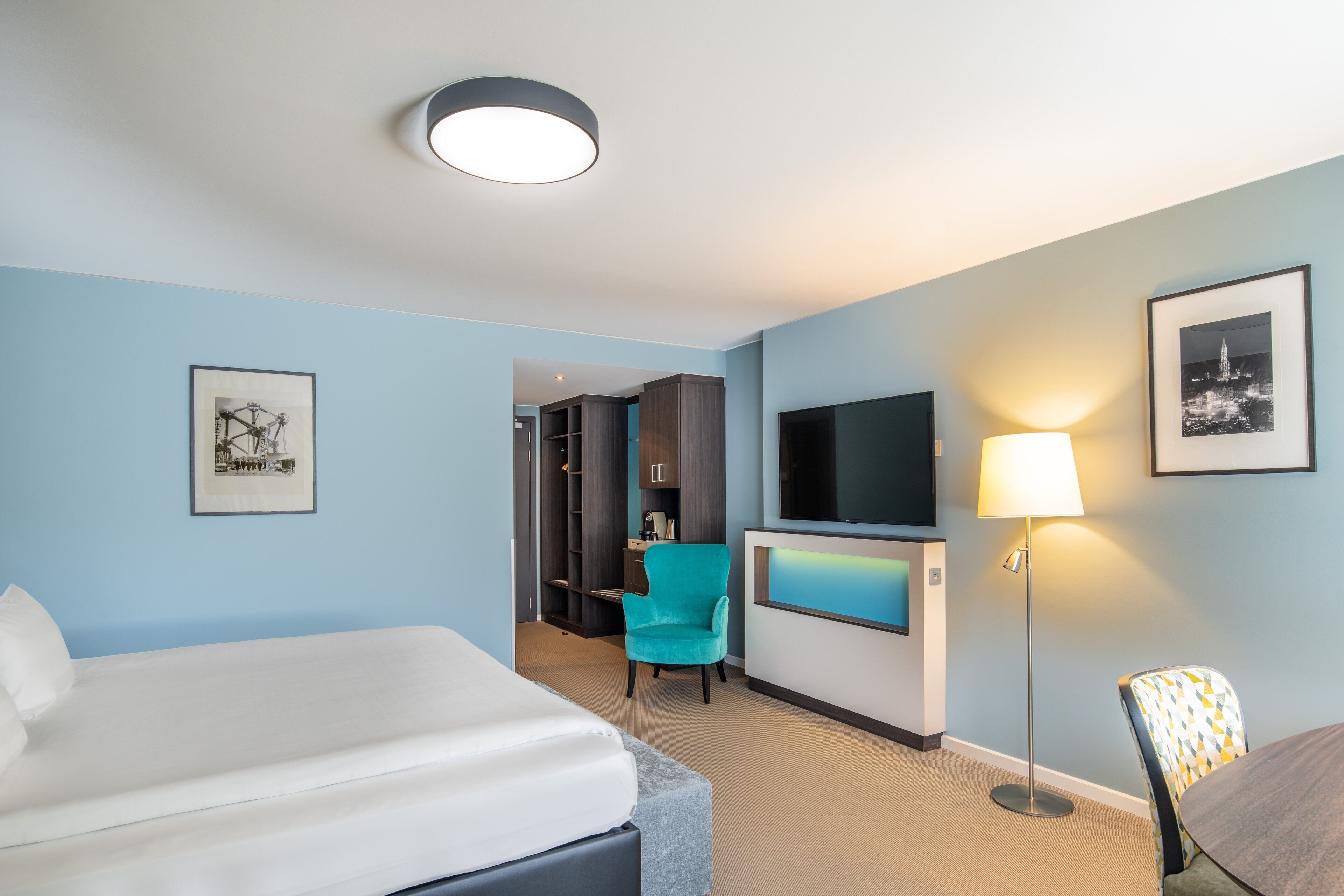 Een hotelkamer met een bed, een bureau, een stoel, een televisie en een lamp.
