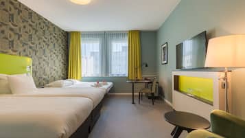 Habitación de hotel con dos camas, un escritorio, una silla, un televisor y una ventana con cortinas.