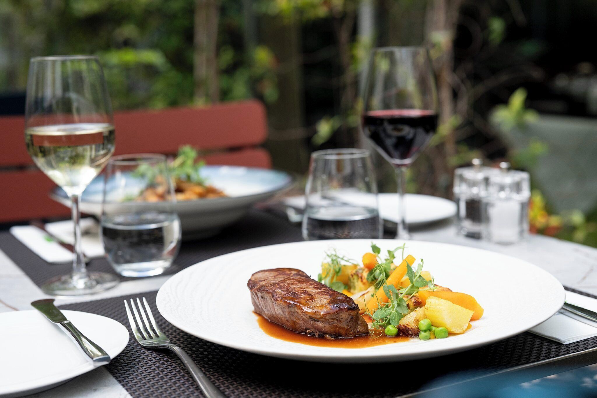 Une table à manger avec des assiettes remplies de nourriture, des verres à vin et des couverts.