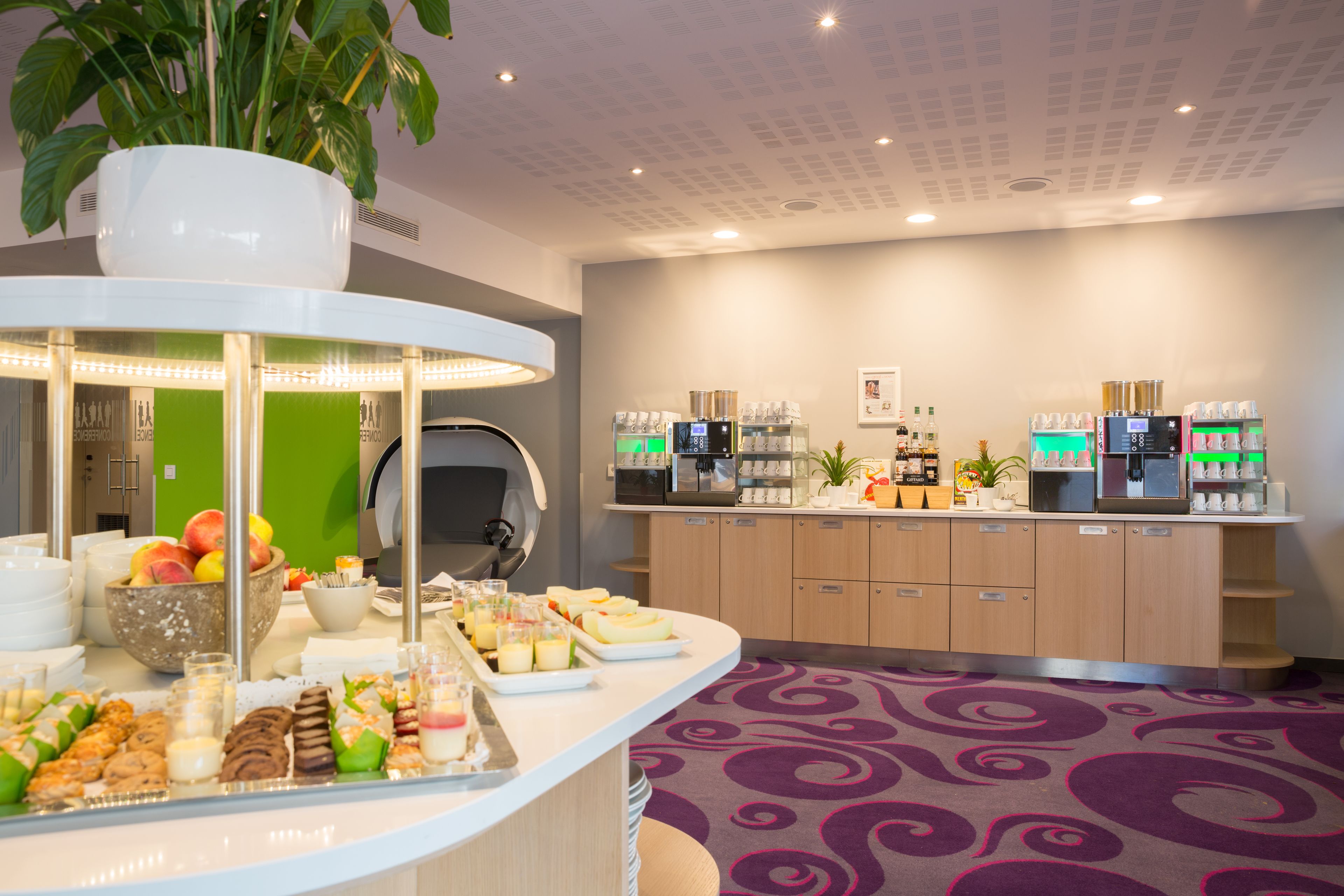 A hotel reception area with a counter displaying snacks, a coffee machine, and a plant.