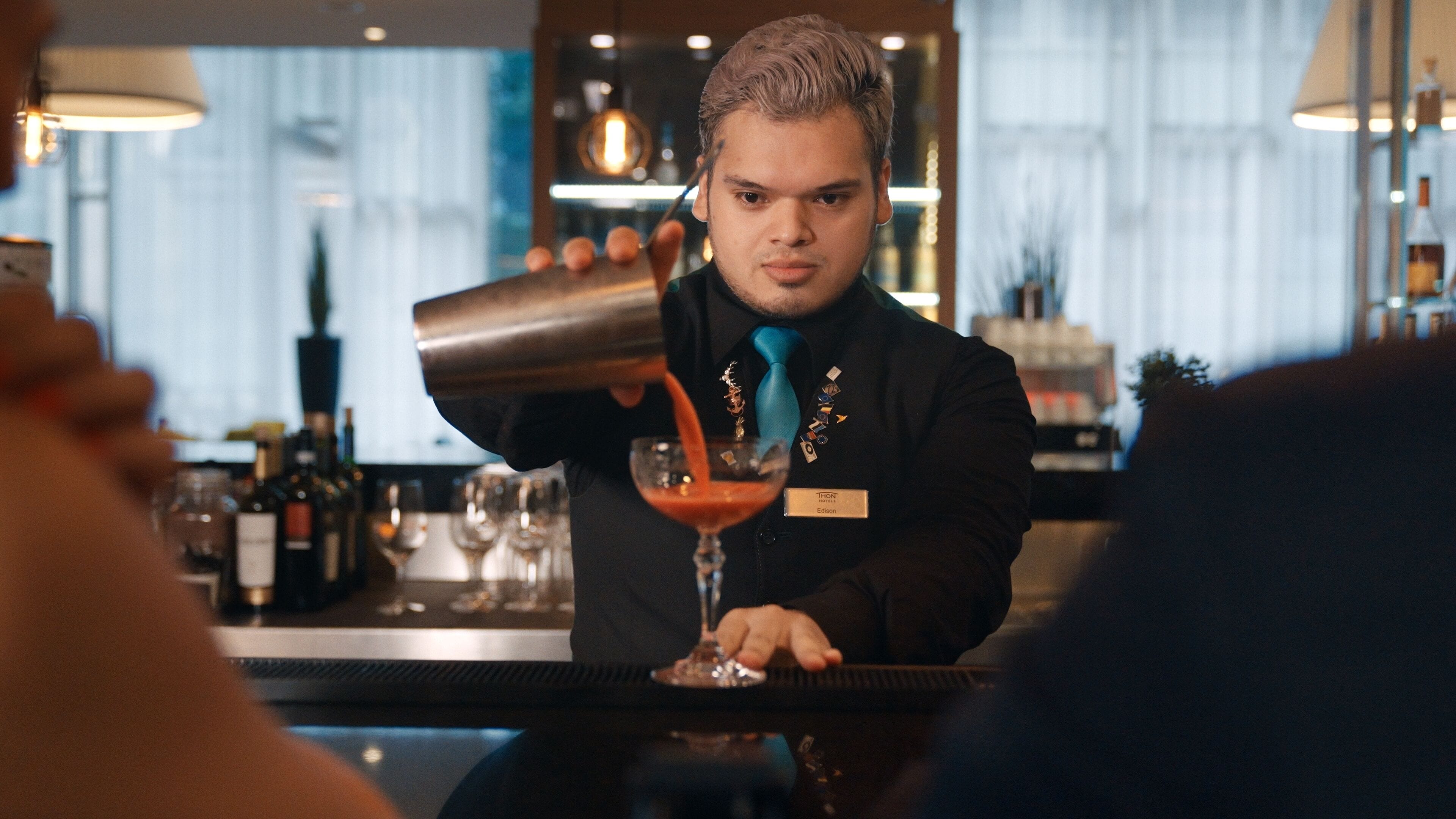A bartender pouring a drink into a glass.