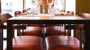 A dining table set with glasses and cutlery, surrounded by leather chairs.