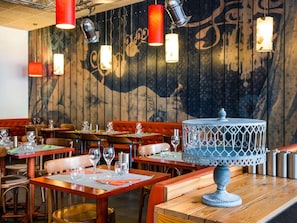 A restaurant interior with wooden panel walls, red upholstered booths, and hanging pendant lights. - ibis Styles Lyon Centre - Gare Part Dieu Hotel (Lyon)