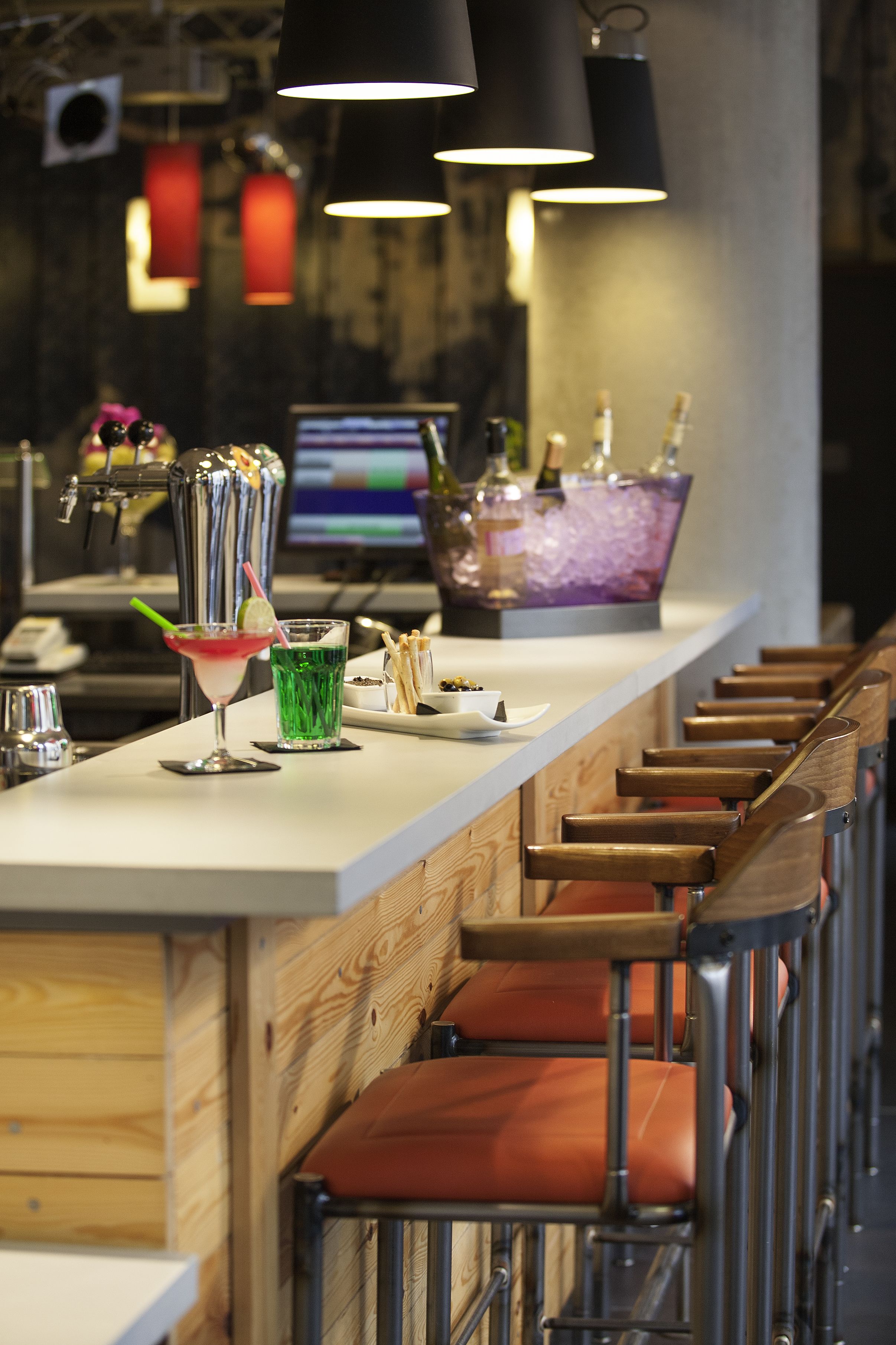 Eine Bar mit einer langen Theke, Barhocker und einem Computerbildschirm im Hintergrund.