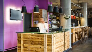 A reception area with a wooden counter, bar stools, and a purple wall. - ibis Styles Lyon Centre - Gare Part Dieu Hotel (Lyon)