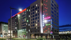 A multi-story hotel with illuminated signage for 'Mercure' and 'Ibis' brands, large windows, and a modern architectural design. - ibis Styles Lyon Centre - Gare Part Dieu Hotel (Lyon)