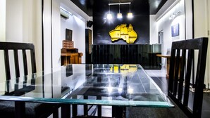 Uma sala de conferências moderna com uma mesa de vidro, paredes em preto e branco e uma obra de arte amarela singular no teto.