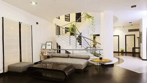 Um interior moderno com uma escada curva, um sofá modular e uma mesa de centro.