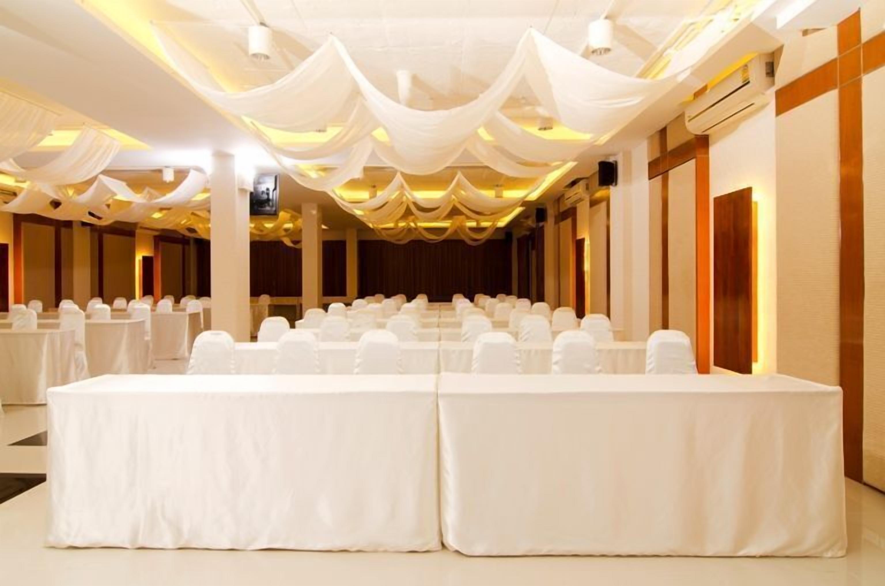 A banquet hall with rows of tables covered in white tablecloths and chairs.