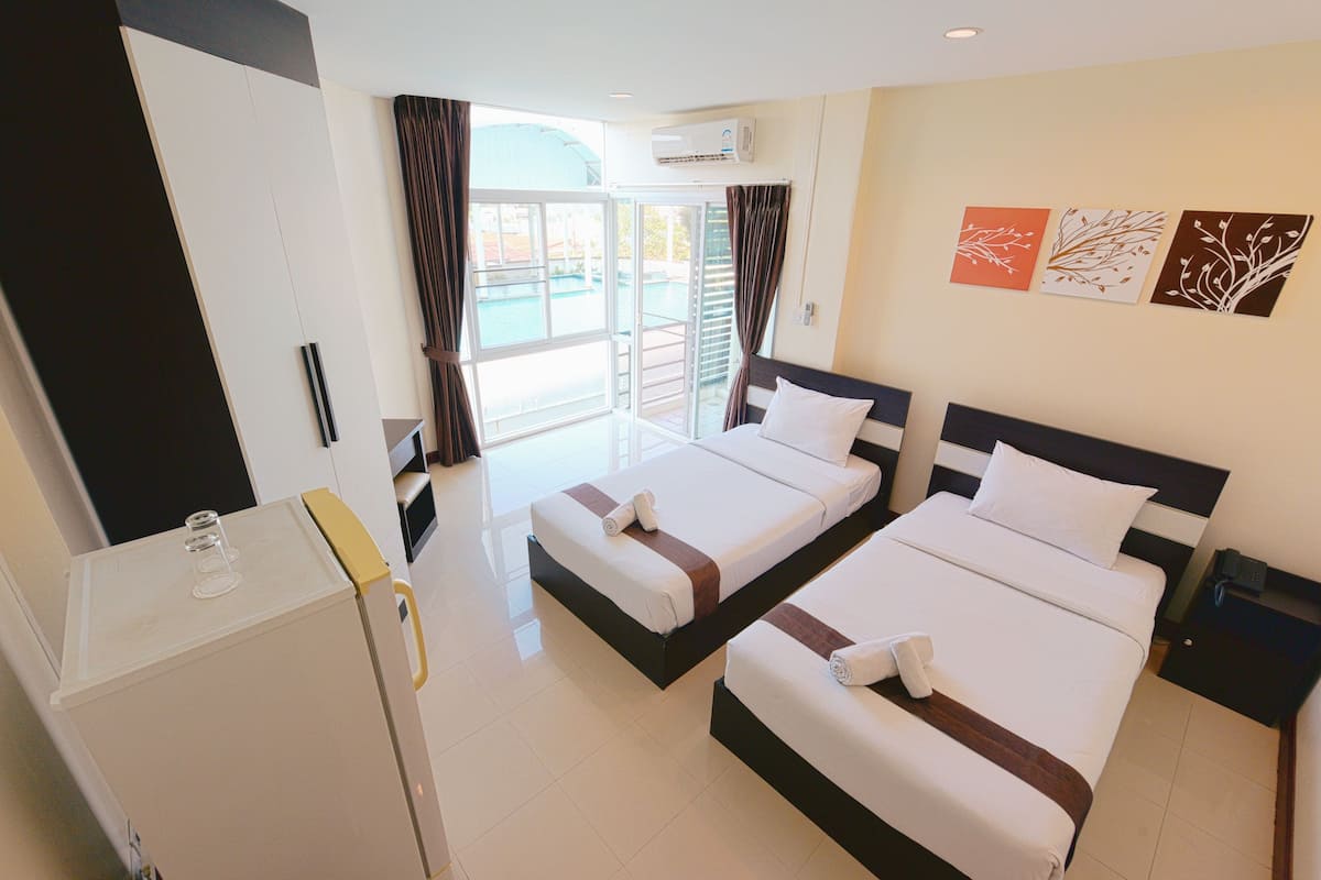 Habitació d'hotel amb dos llits, un minibar i vista a la piscina.