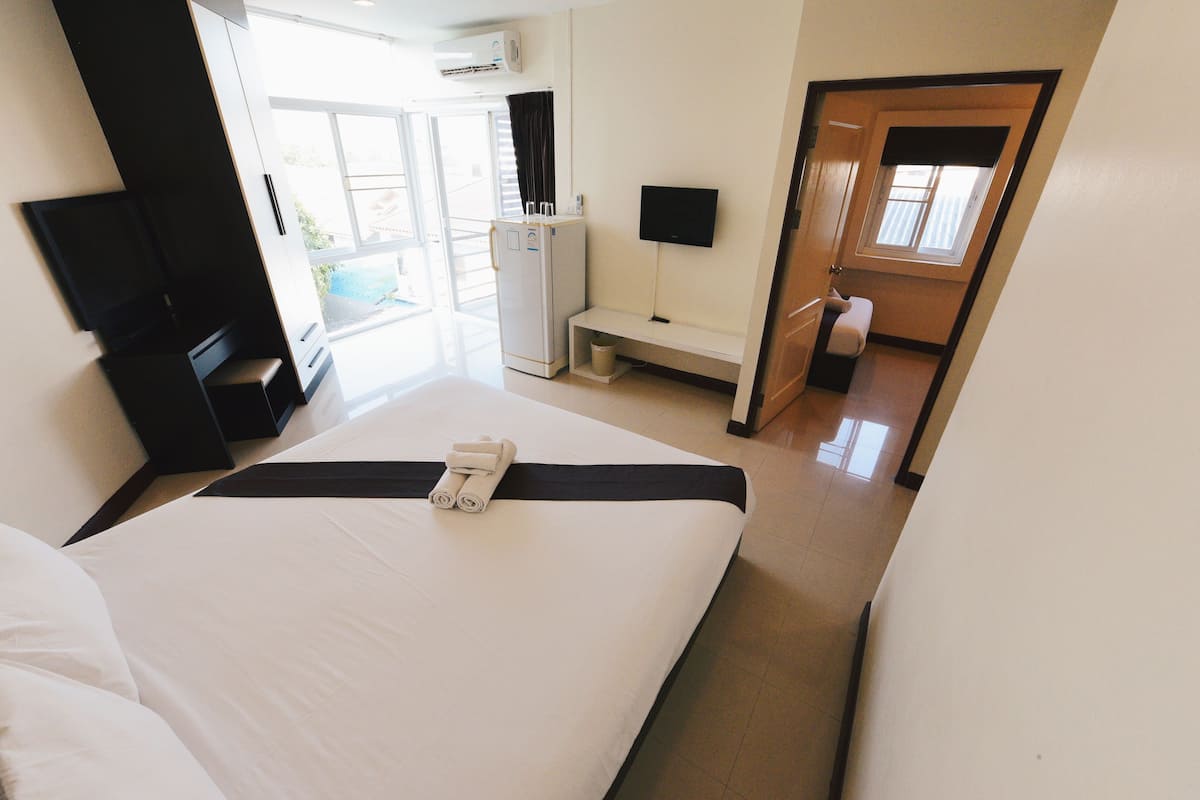Habitació d'hotel amb un llit, una taula, una televisió i una finestra.