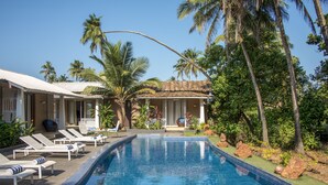 A swimming pool with lounge chairs and palm trees. - Casa Vagator (Vagator)