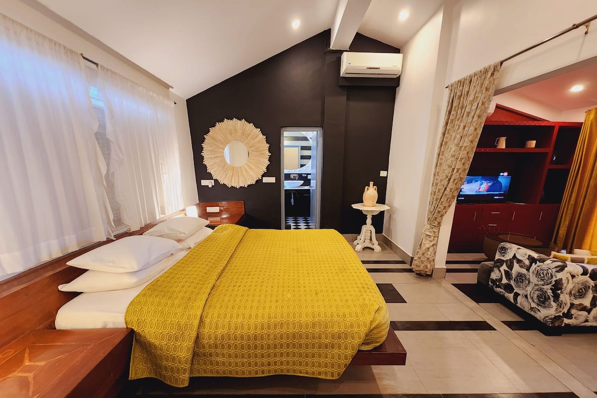 A modern bedroom with a large bed, a TV, and a minibar.