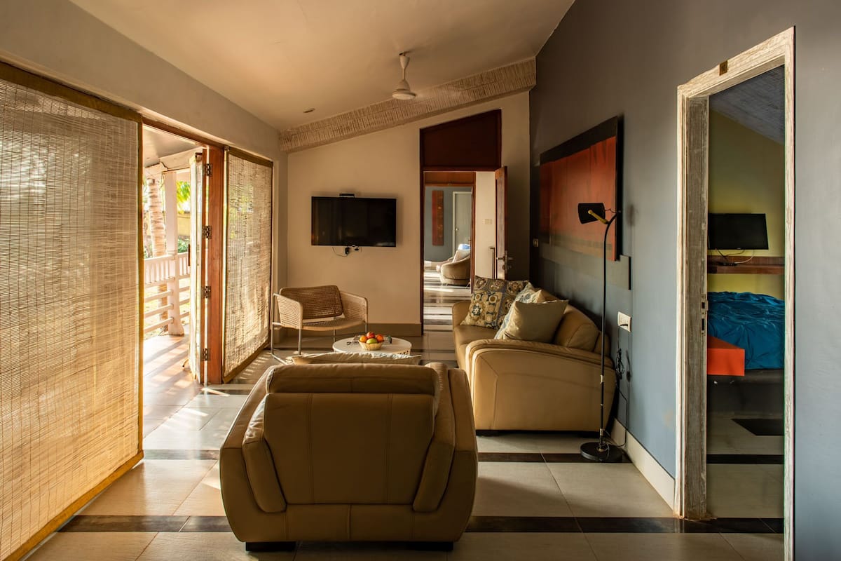 A spacious living area with a sofa, a chair, and a television mounted on the wall.