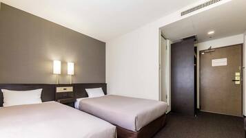 A hotel room with two beds, a nightstand, a lamp, and a door with a sign.