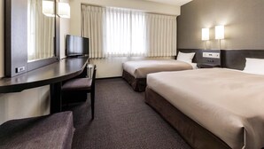 Une chambre d’hôtel avec deux lits, un bureau avec une télévision, une chaise et un grand miroir.