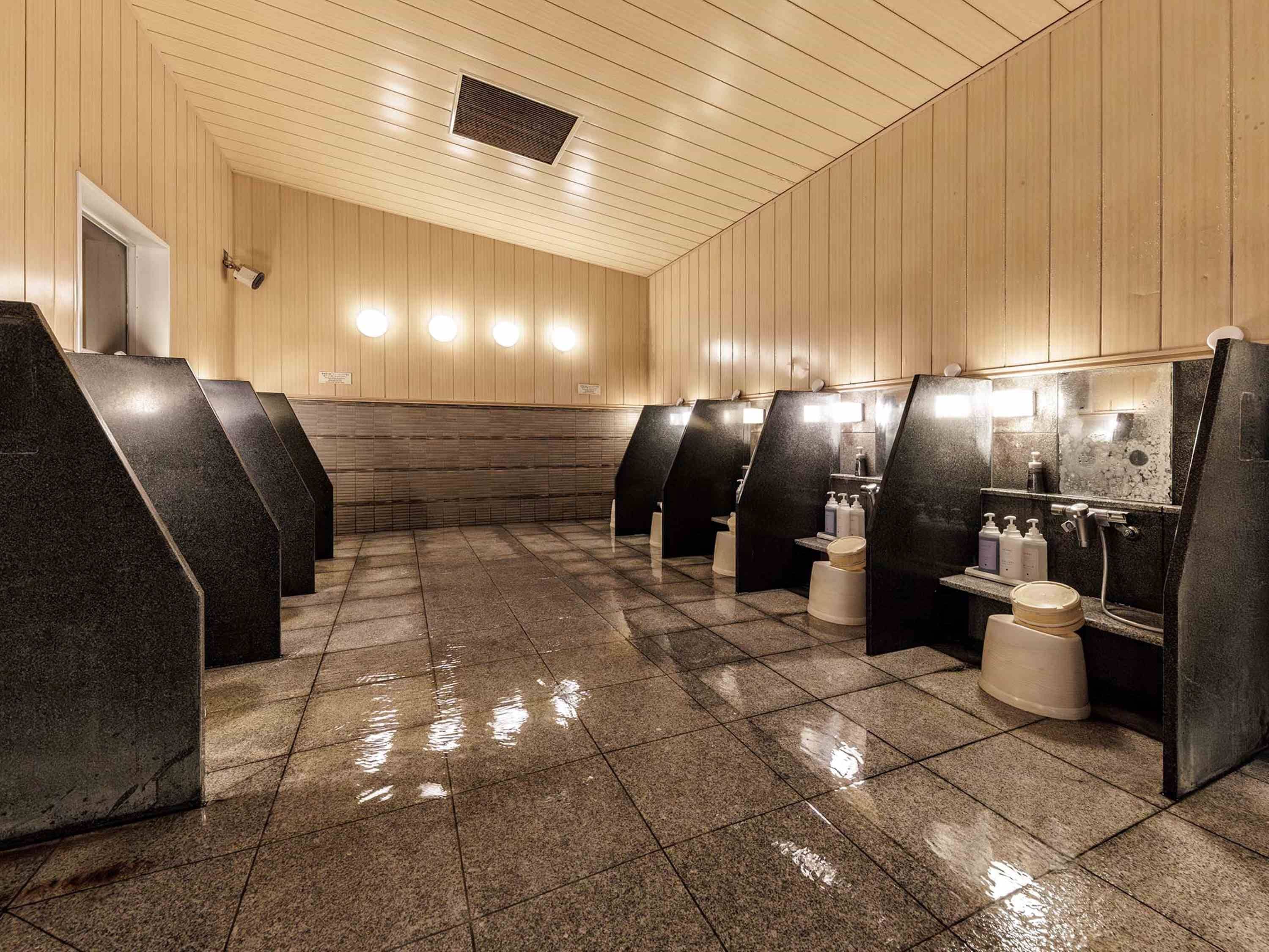 A public restroom with multiple stalls, tiled floors, and wooden panel walls.