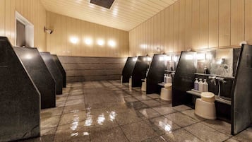 A public restroom with multiple stalls, tiled floors, and wooden panel walls.