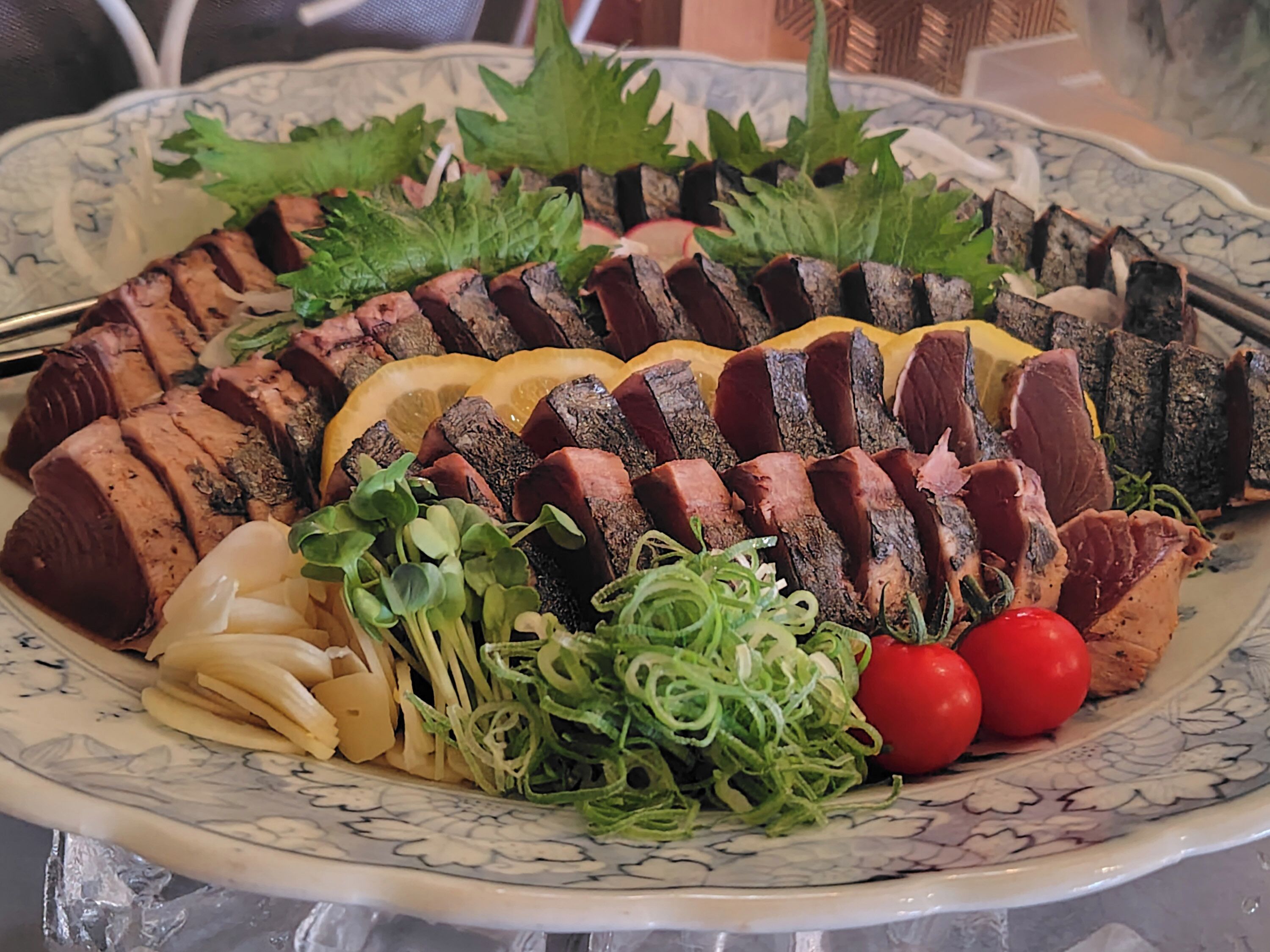 Une assiette de viande tranchée, garnie de verdure et de légumes.