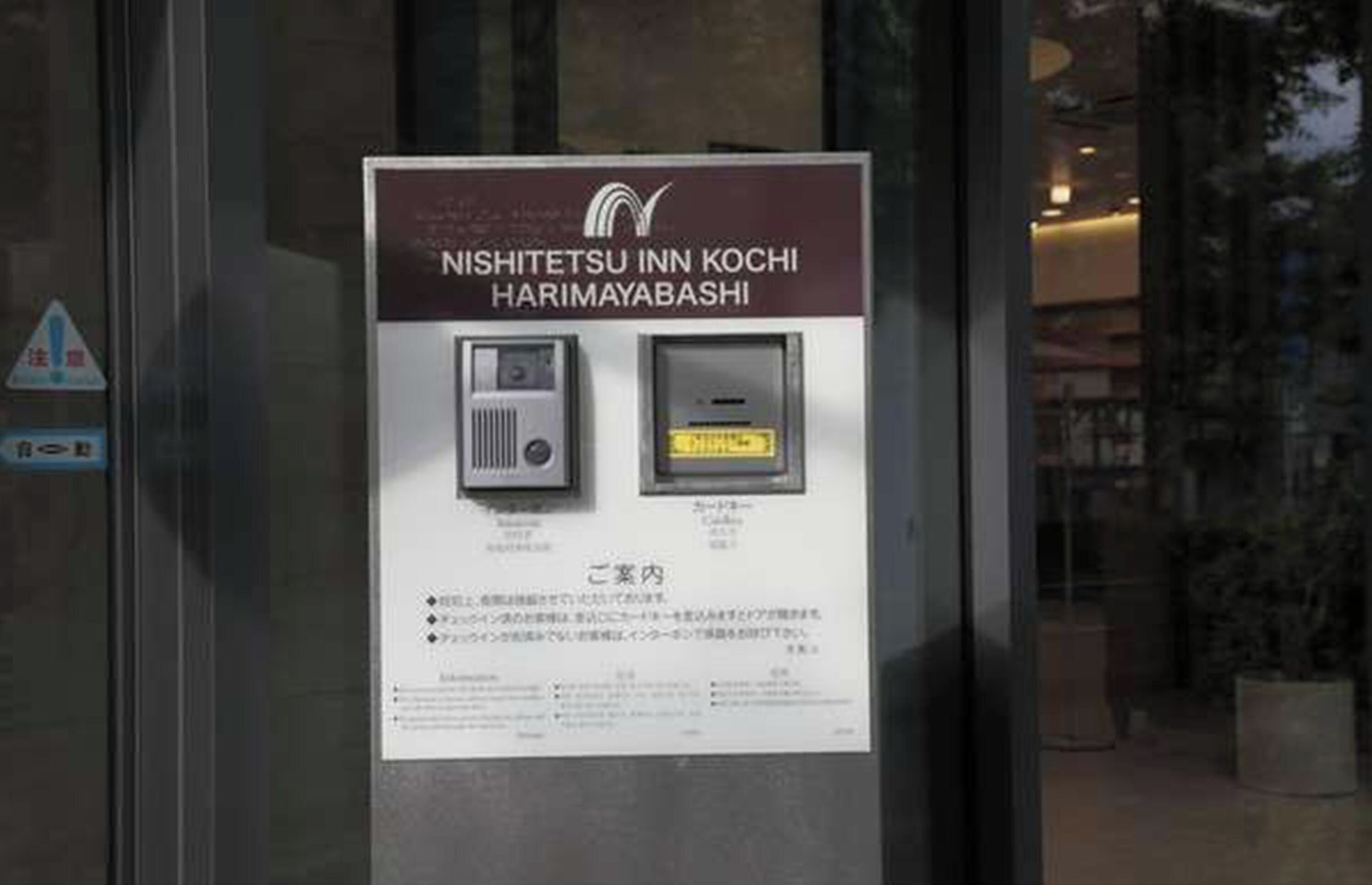 A sign for NISHITETSU INN KOCHI HARIMAYABASHI with a QR code and a small image of a room.