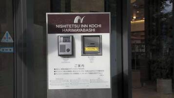 A sign for NISHITETSU INN KOCHI HARIMAYABASHI with a QR code and a small image of a room.