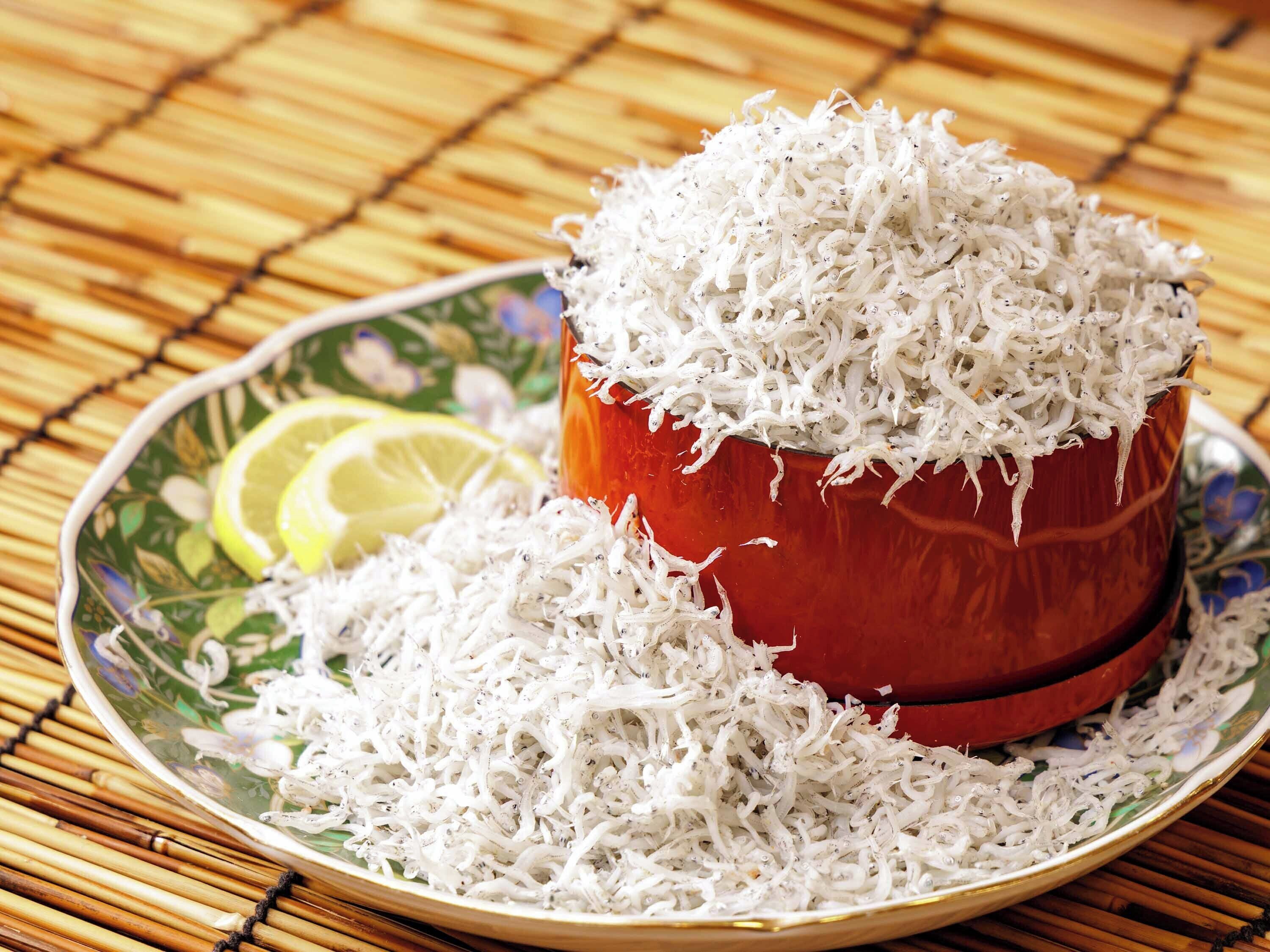 A bowl of shredded white substance, possibly coconut, on a decorative plate with a slice of lemon.