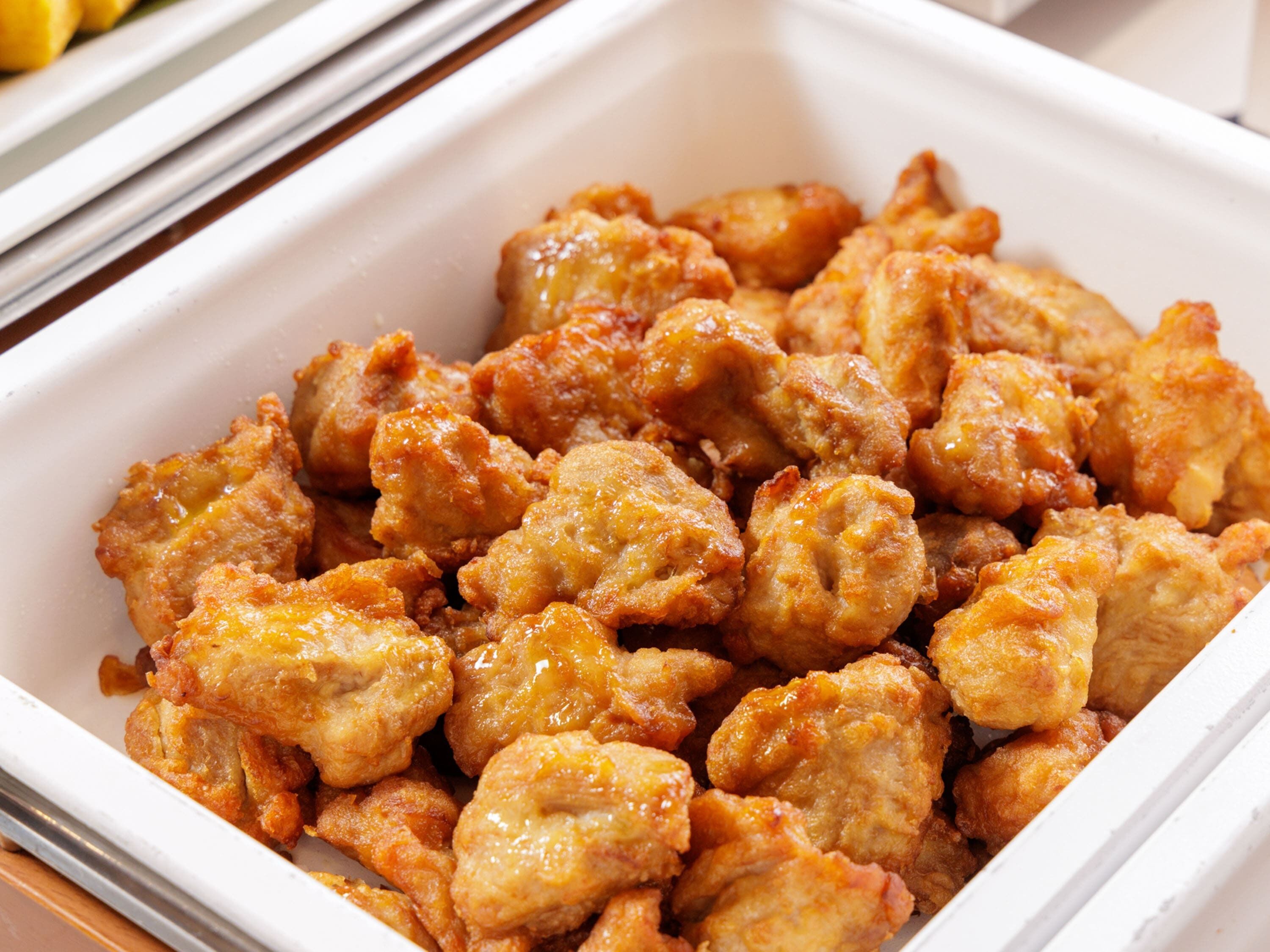 A white rectangular container filled with fried chicken pieces.