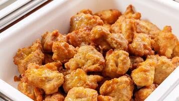 A white rectangular container filled with fried chicken pieces.