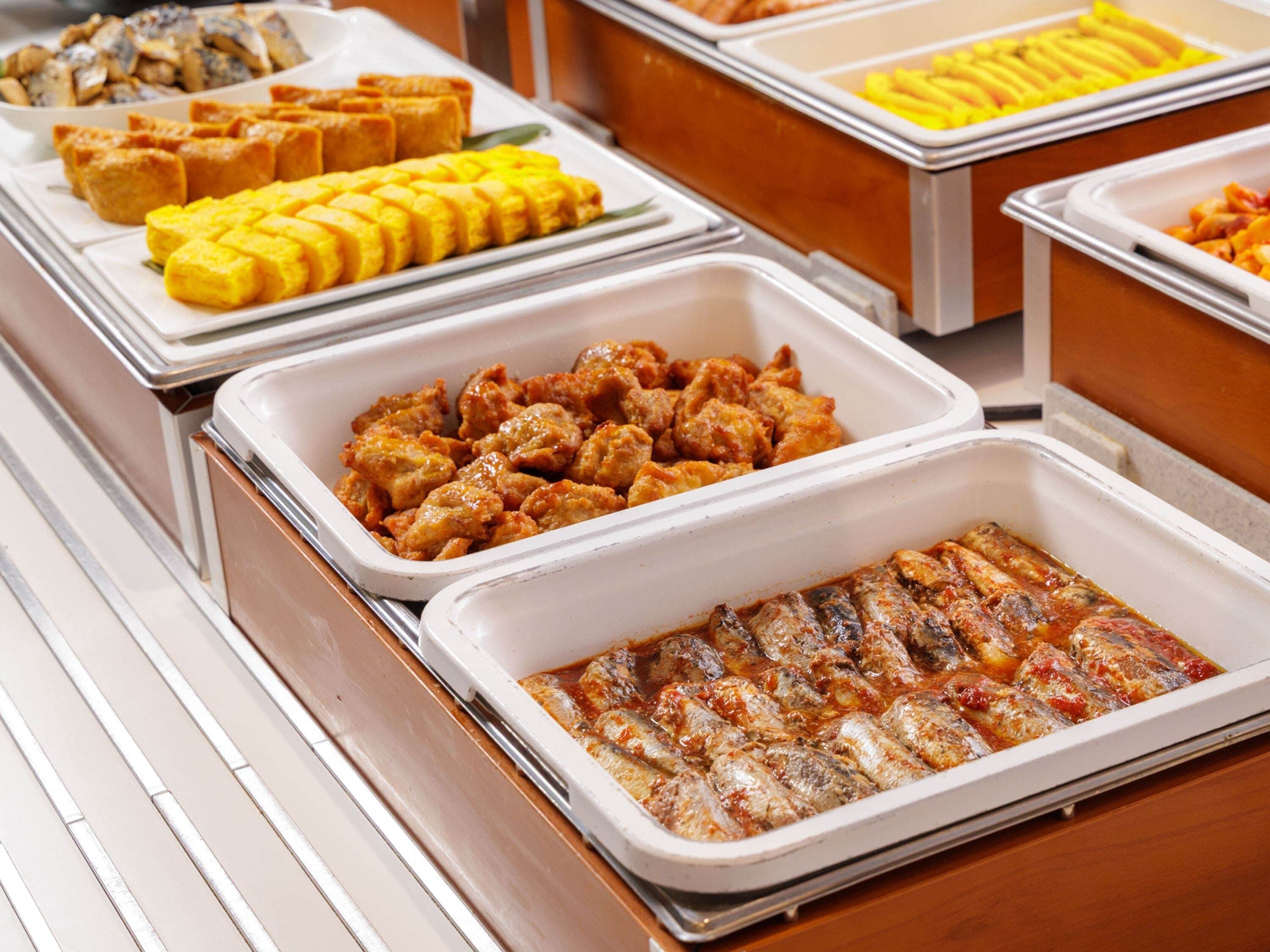 Ein Buffet mit verschiedenen Speisen, darunter frittierte Gerichte, gegrilltem Fisch und anderen zubereiteten Speisen.