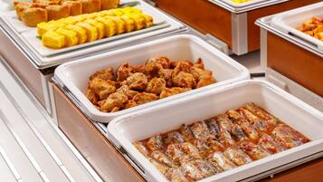 Ein Buffet mit verschiedenen Speisen, darunter frittierte Gerichte, gegrilltem Fisch und anderen zubereiteten Speisen.