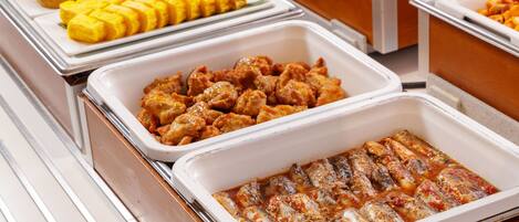 A buffet with various dishes including fried items, grilled fish, and other prepared foods.