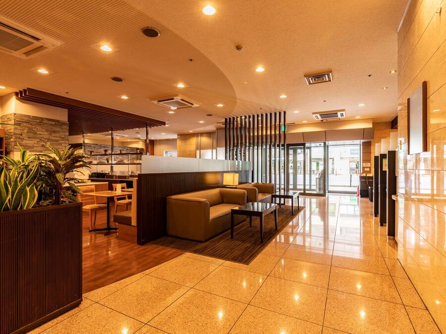 A modern lobby with a seating area, a reception desk, and a large window.