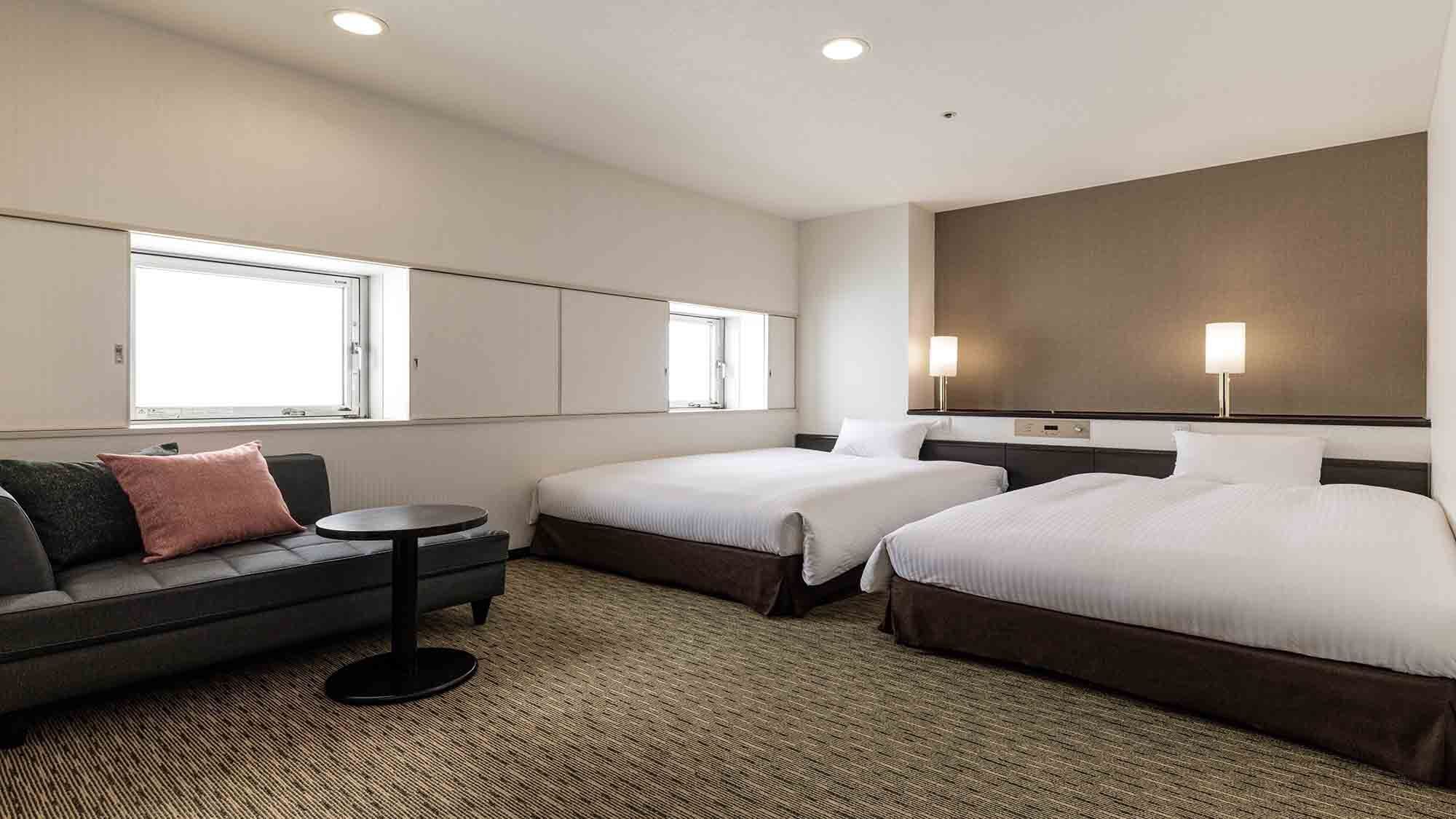 A hotel room with two beds, a sofa, a small table, and a large mirror.