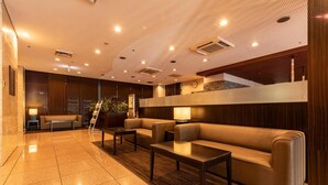 A modern lobby with a sofa, tables, and a staircase. - Nishitetsu Inn Kurosaki (Kitakyushu)
