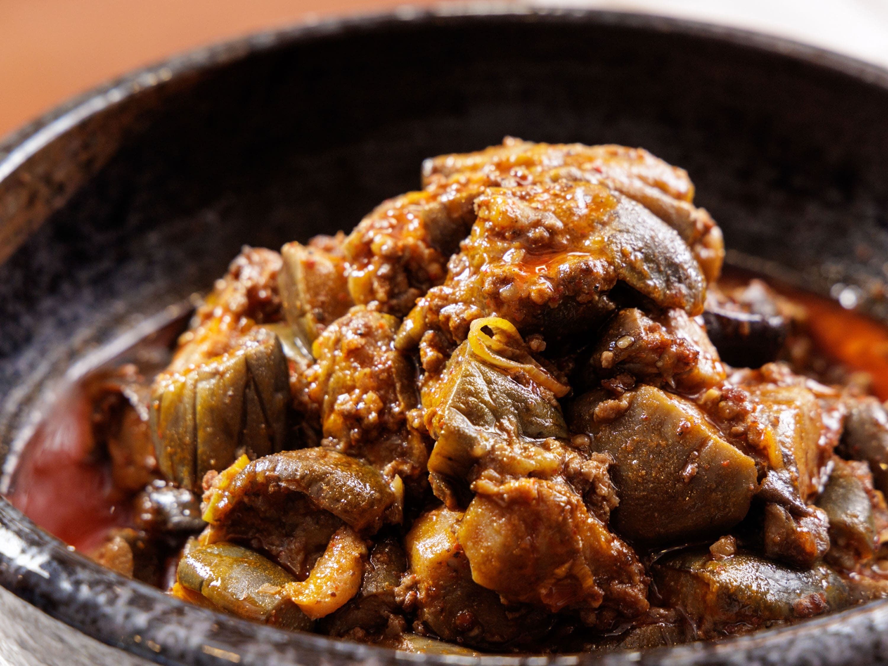 Une vue rapprochée d’un plat contenant des morceaux de viande et des légumes dans une sauce.