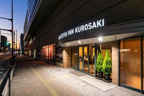 Entrada de un hotel con un cartel que dice "Nishitetsu Inn Kurosaki".