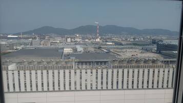 A large industrial facility with multiple buildings, a prominent smokestack, and a mountainous backdrop.