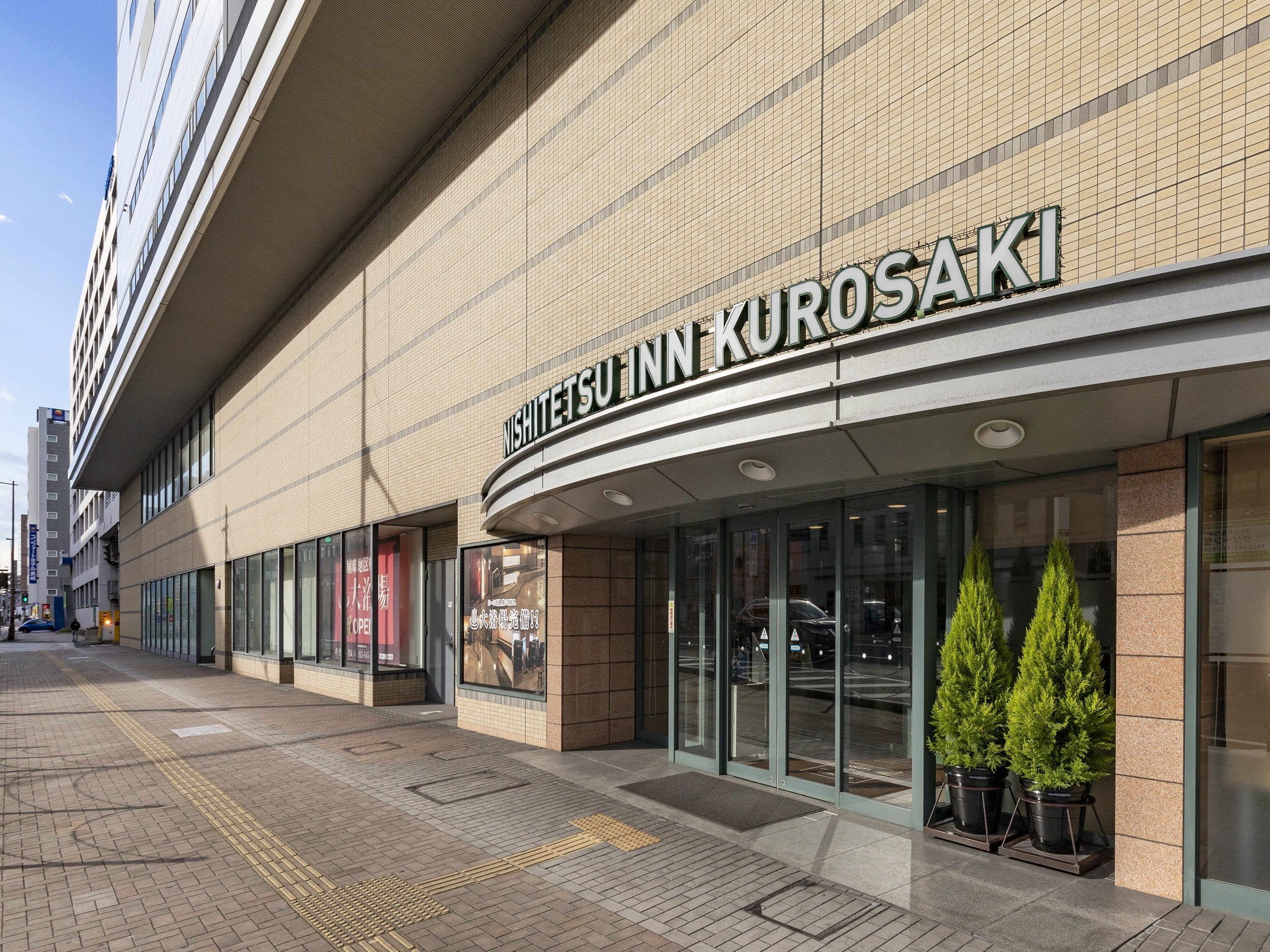 A building with a sign reading "NISHITETSU INN KUROSAKI".