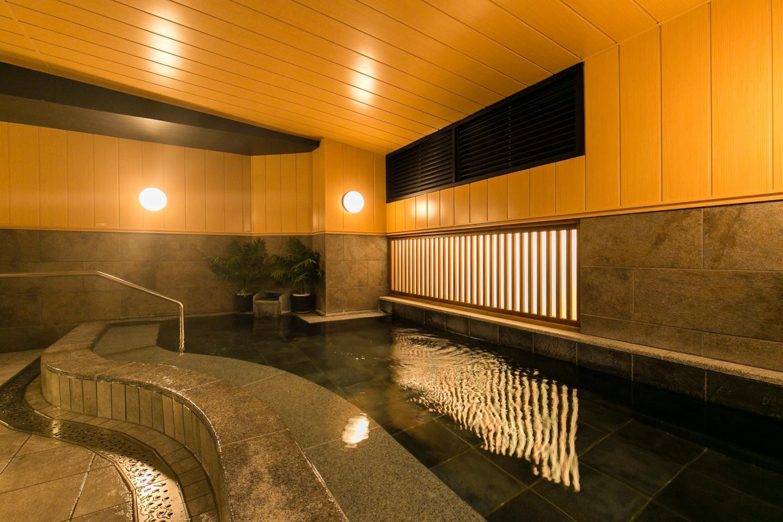 Área interna de piscina moderna com escada curva, painéis de madeira e um recurso de água.