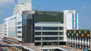 A modern building with a prominent "COM CITY" sign, featuring a glass facade and a covered pedestrian area.
