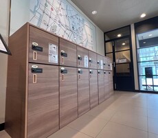 A row of lockers with numbered labels, a map on the wall, and a view through a glass door.