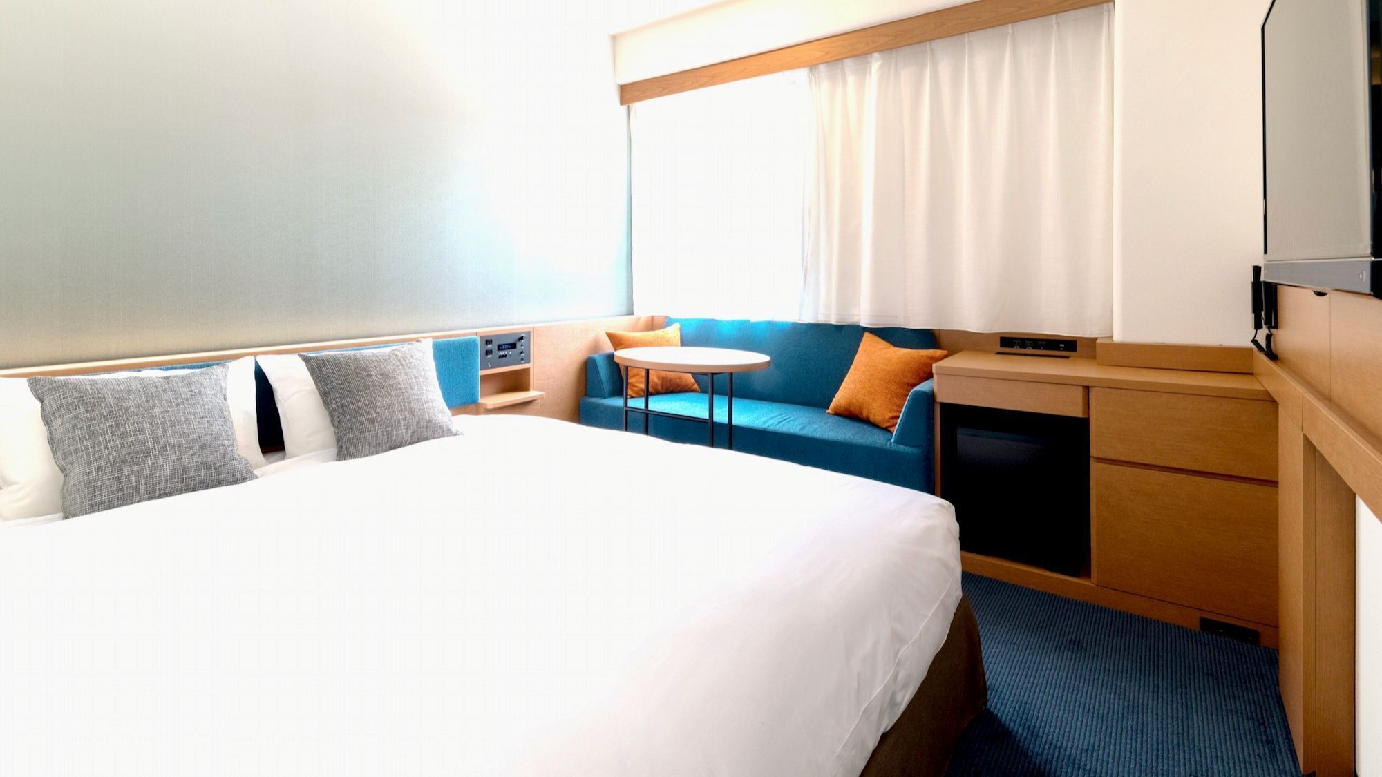 Une chambre d’hôtel avec un grand lit, une petite table, un canapé et une télévision.