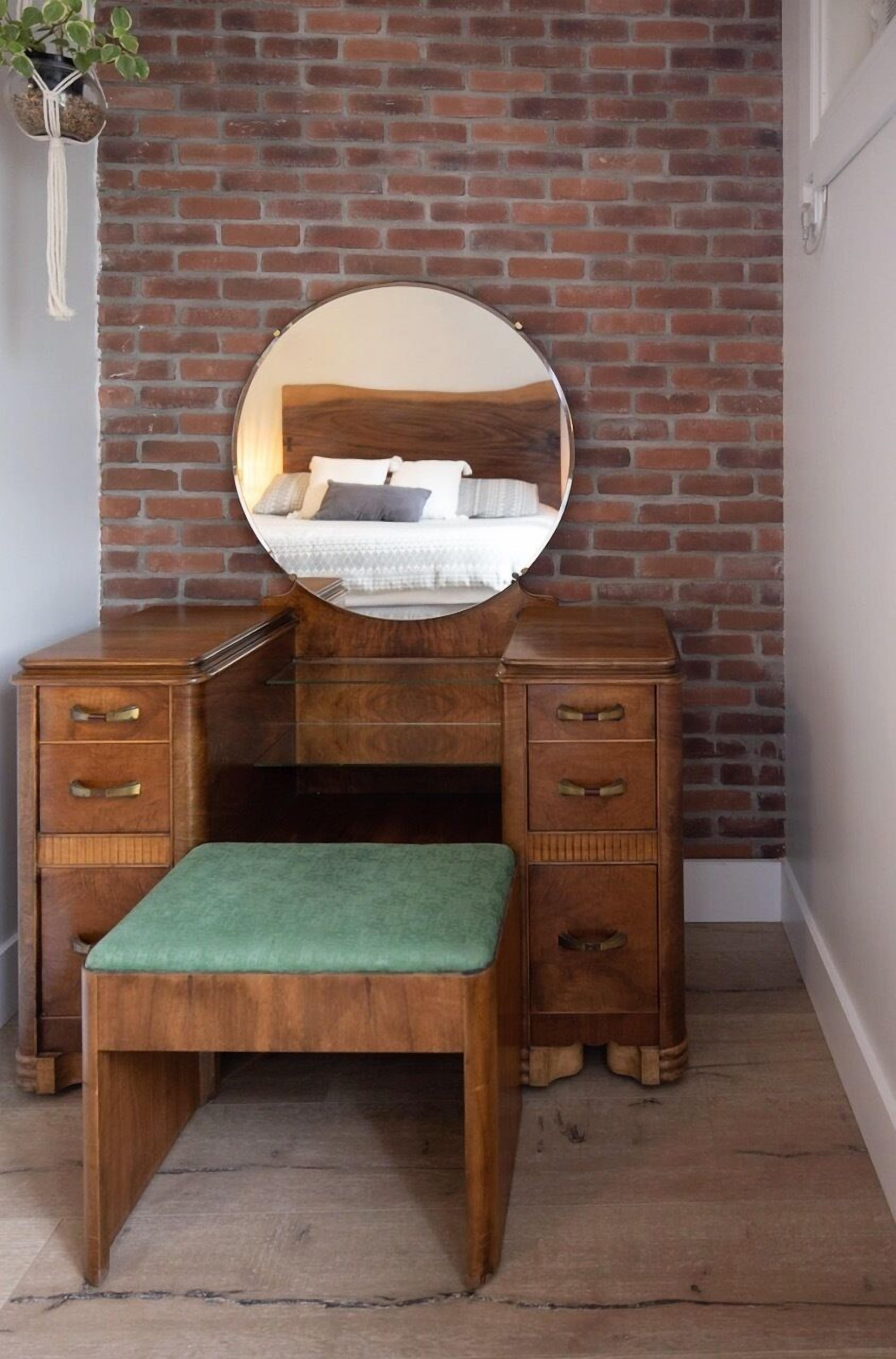 A wooden vanity with a mirror, drawers, and a bench.
