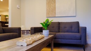 Un salon moderne avec un canapé gris, une table basse en bois et une plante en pot.