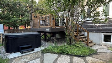 A backyard with a hot tub, stone pathway, and a wooden deck.
