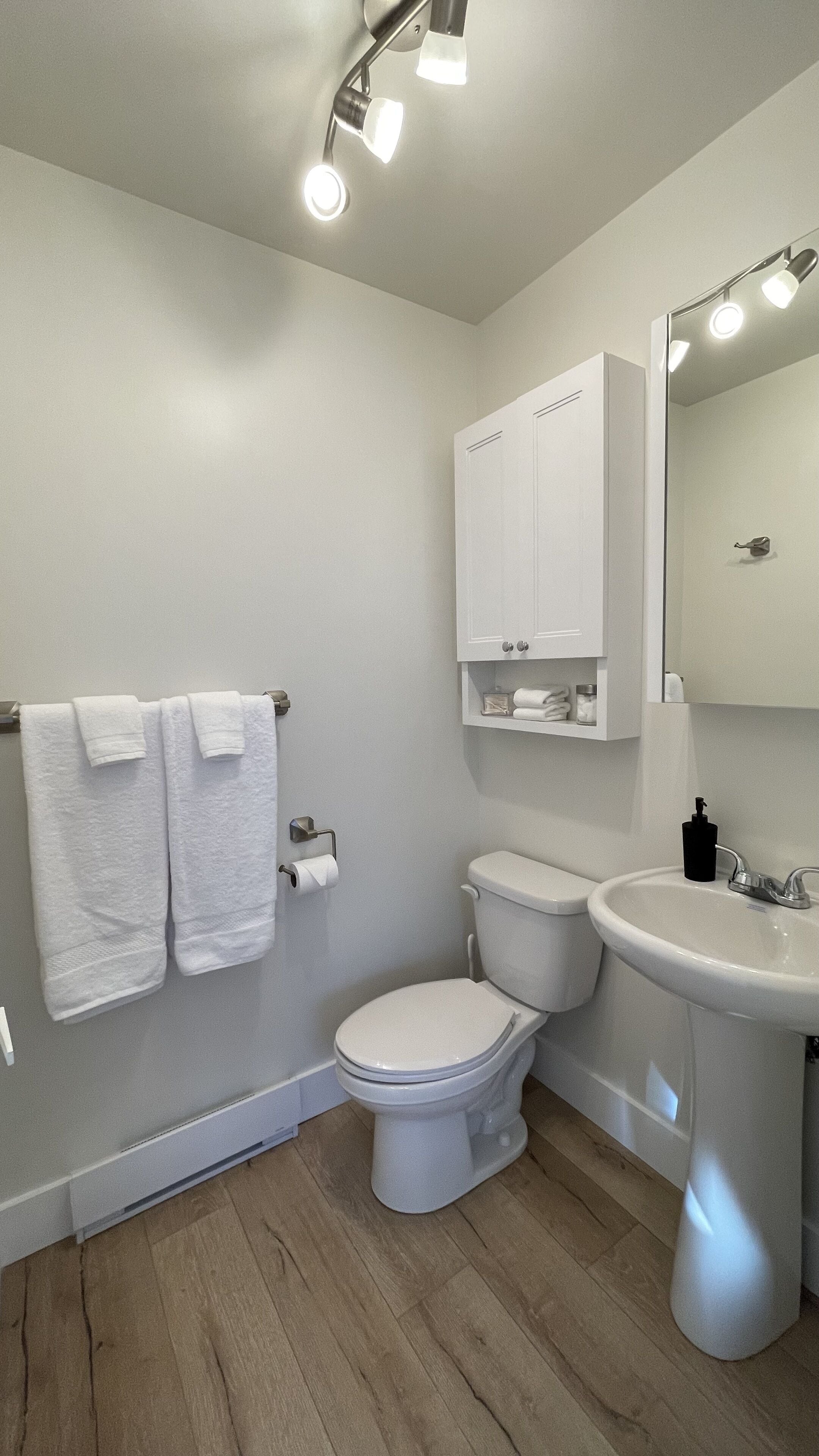 A modern bathroom with a toilet, sink, and towel rack.