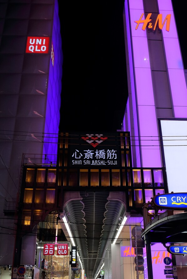 Un edificio con varios escaparates de tiendas, incluyendo UNIQLO y H&M, y una gran pantalla digital.