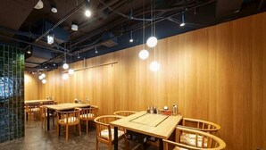 A restaurant interior with wooden tables and chairs, pendant lighting, and a tiled backsplash. - Nishitetsu Inn Shinsaibashi (Osaka)